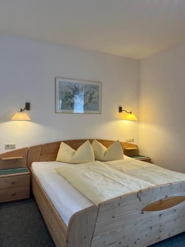 1 dormitorio con 1 cama grande de madera y 2 lámparas en Ferienhaus Ahorn, en Neustift im Stubaital