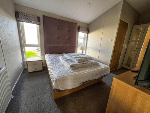 a bedroom with a bed in a room with two windows at Beautiful Lodge With Decking In Hunstanton At Manor Park Ref 23195k in Hunstanton