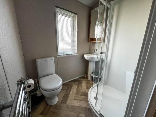 y baño con aseo, lavabo y ducha. en Beautiful Lodge With Decking In Hunstanton At Manor Park Ref 23195k en Hunstanton