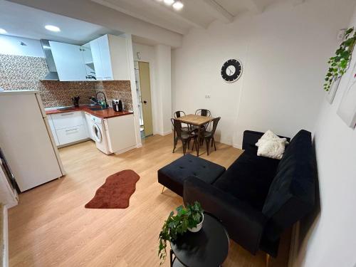 ein Wohnzimmer mit einem schwarzen Sofa und einer Küche in der Unterkunft Barceloneta beach house in Barcelona