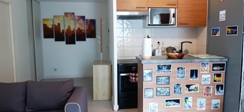 una cucina con divano e bancone con foto sul muro di Ravissant Appartement T2 proche du centre-ville a Villefranche-sur-Saône