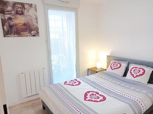 una camera da letto con un letto con cuscini rosa e bianchi di Ravissant Appartement T2 proche du centre-ville a Villefranche-sur-Saône