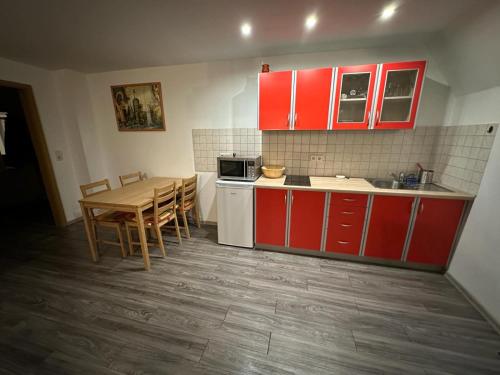une cuisine avec des placards rouges, une table et des chaises dans l'établissement Apartment Emilia, à Leipzig