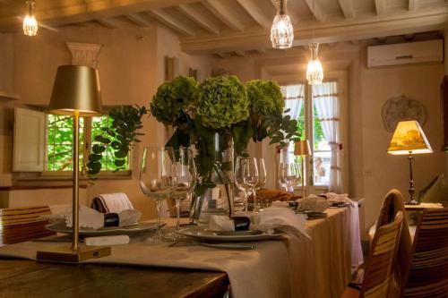 Locanda Sant' Agostino في لوكّا: طاولة عليها أكواب و إناء من الزهور
