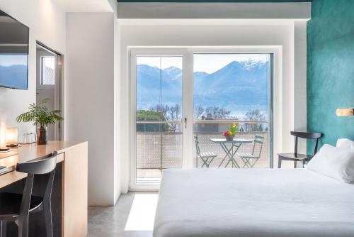 a hotel room with a bed and a view of a balcony at Riva Rooms & Studios - Check-In 24hr in Locarno