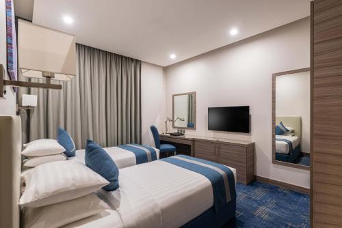 a hotel room with two beds and a television at Best Western Plus Tabuk City Center in Tabuk