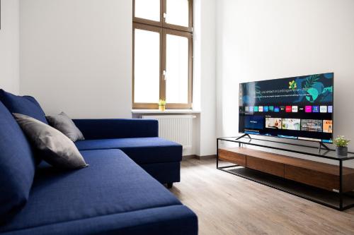 a living room with a blue couch and a flat screen tv at Apartments am Neuen Theater - Altstadt - Zentral - Küche - Wifi - Powered by Ko-Living in Halle an der Saale