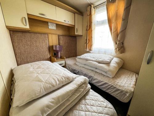 two beds in a small room with a window at Lovely Caravan At Manor Park, Nearby Hunstanton Beach In Norfolk Ref 23067s in Hunstanton
