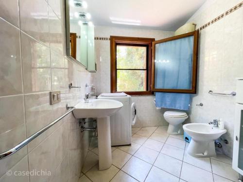 uma casa de banho com um lavatório, um WC e uma janela. em Torre di Chia Holiday Home em Chia