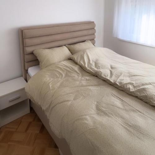 a bedroom with a large bed with a night stand at ZARA Apartman Živinice in Živinice
