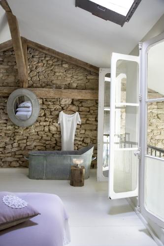 La salle de bains est pourvue d'un mur en pierre et d'une baignoire. dans l'établissement Bassiviere Barn Chic, à Saint-Étienne-de-Villeréal