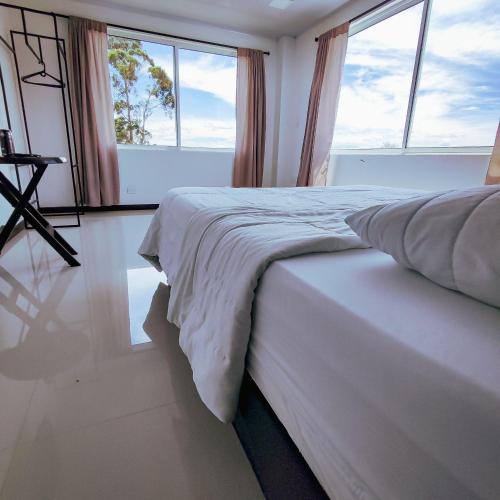 a bedroom with a large bed with windows at Hotel Ocaso Marinilla in Marinilla