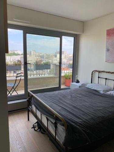 une chambre avec un lit et une grande fenêtre dans l'établissement Magnificent Penthouse panaramic view of Paris, à Paris