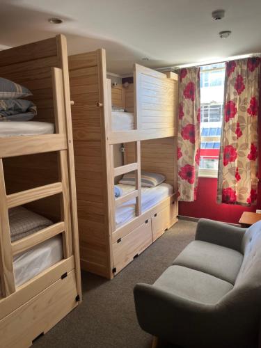 a room with bunk beds with a couch and a chair at UpTown Backpackers in Dunedin