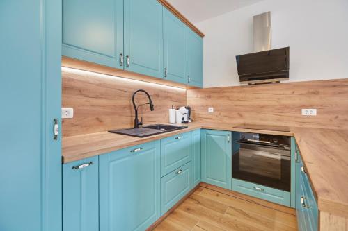 a kitchen with blue cabinets and a sink at Apartments Svitnjak in Bovec