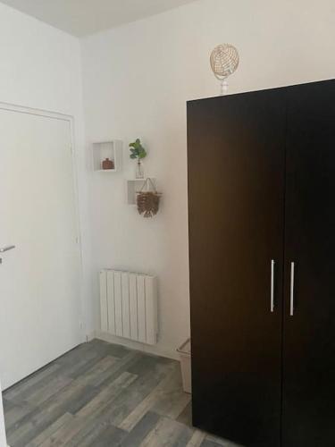 une armoire noire dans une pièce avec un mur blanc dans l'établissement Studio N°2 hyper centre, à Châteaubriant