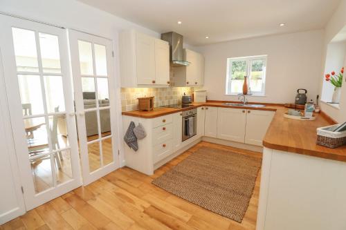 a kitchen with white cabinets and wooden floors at Mariners Rest in Gorran Haven