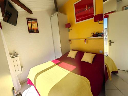 - une chambre dotée d'un lit avec une couverture jaune et rouge dans l'établissement Superbe T2 climatisé à 50m de la plage, piscine, parking, 5 pers - FR-1-607-97, au Cap d'Agde