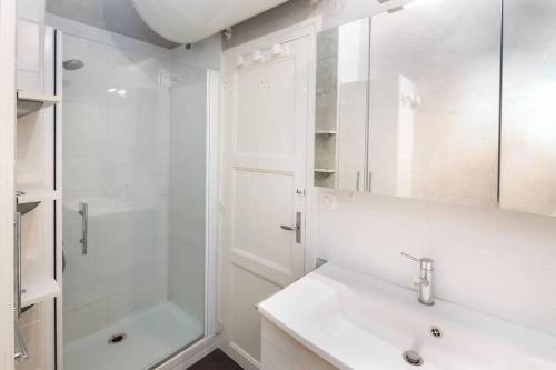 une salle de bain blanche avec un lavabo et une douche dans l'établissement Bel appartement avec vue sur la baie de Dinard, à Dinard