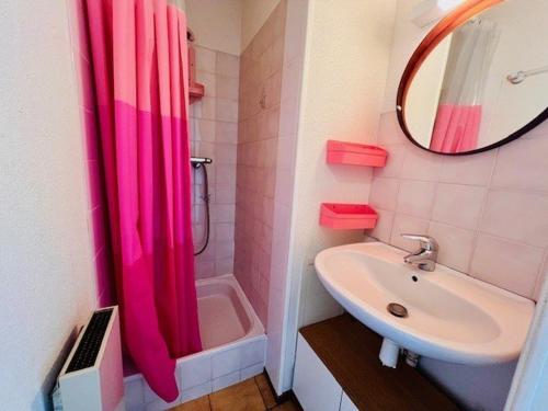 La salle de bains est pourvue d'un rideau de douche rose et d'un lavabo. dans l'établissement Charme à Quiberon : 2 pièces cosy, proche plage, balcon sud, parking inclus - FR-1-478-266, à Quiberon