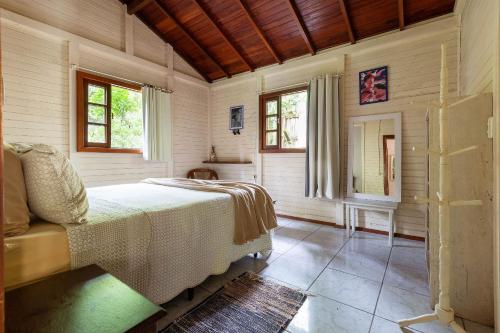 um quarto com uma cama e duas janelas em Sítio Águas Encantadas - Cachoeira e Águas termais em Santo Amaro da Imperatriz