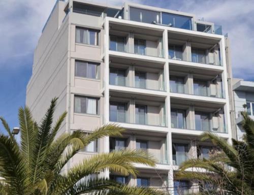 a tall white building with palm trees in front of it at CW Athens Riviera Suite in Athens