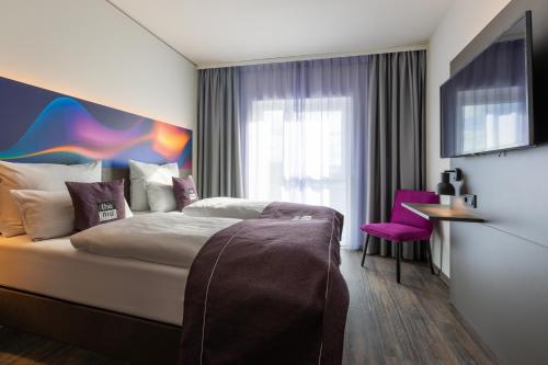 a hotel room with a bed and a purple chair at the niu Wave in Karlsruhe