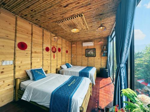 two beds in a room with wooden walls at Trang An Moon Garden Homestay in Ninh Binh