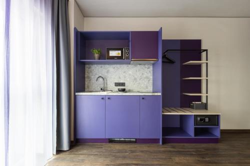 a kitchen with purple cabinets and a sink at Holiday Inn-the niu, Wave Karlsruhe Oststadt by IHG in Karlsruhe