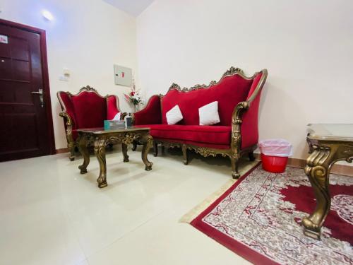 a living room with two red chairs and a table at Serene Nest in Umm Al Quwain