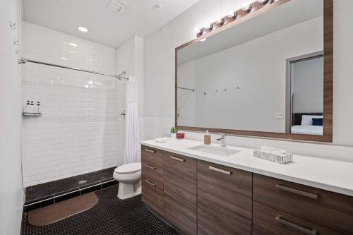 a bathroom with a sink and a toilet and a mirror at Luxurious Downtown Apt - Pool, Laundry, Parking in Dallas