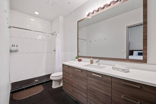 Un baño con lavabo, inodoro y espejo. en Stunning Downtown Apartment with Pool, Laundry, Parking, en Dallas