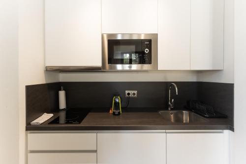 una cocina con fregadero y microondas en La Casa de la Alameda, en Málaga