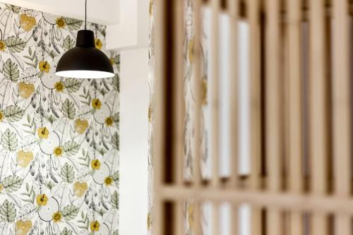 una lámpara colgada de una pared con un papel pintado floral en Nouveau studio tout équipé Charbonnières les Bains, en Charbonnières-les-Bains