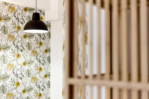 une lampe suspendue à un mur avec un papier peint floral dans l'établissement Nouveau studio tout équipé Charbonnières les Bains, à Charbonnières-les-Bains
