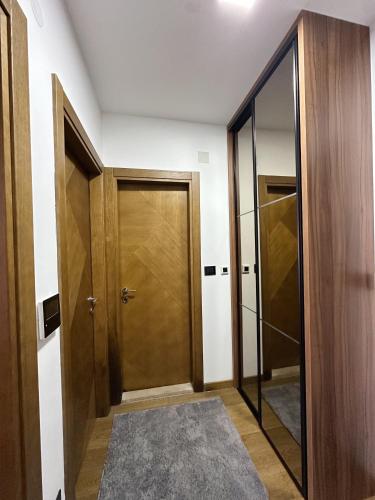 a hallway with a wooden door and a mirror at Hill Homes Mal in Podgorica