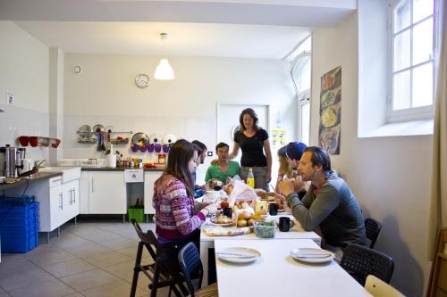 a group of people sitting around a table in a kitchen at Fontaineblhostel hostel & camping near Fontainebleau in La Chapelle-la-Reine