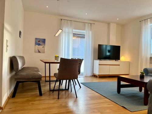 City Living Bischofshofen - Premium Stadtwohnung في بيشوفشوفن: غرفة معيشة مع طاولة وتلفزيون