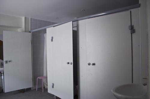 baño con 2 puertas blancas y lavamanos en Fontaineblhostel hostel & camping near Fontainebleau en La Chapelle-la-Reine