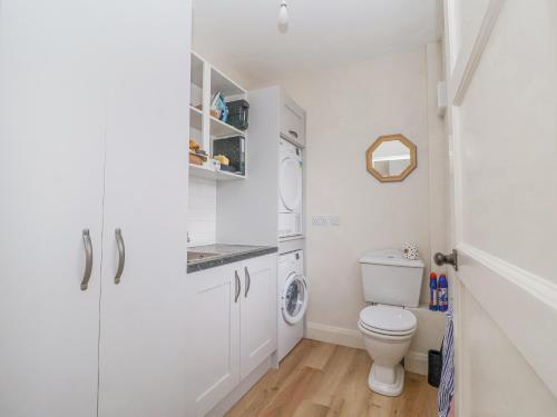 a white bathroom with a toilet and a washing machine at 3 Chantry Cottages in Woodbridge