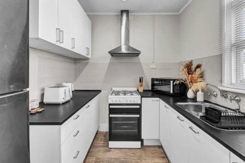 a kitchen with white cabinets and a stove top oven at TheWest36 - Sandy Escape in Henley Beach South