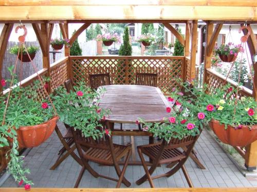 a wooden table and chairs on a patio with flowers at Eszter Vendégház in Tiszafüred