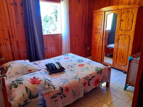 a bedroom with a bed with a flowered blanket and a window at Le muguet sauvage in Le Tampon