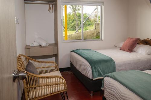 a bedroom with two beds and a window and a chair at Alto Bonito Campestre in Circasia