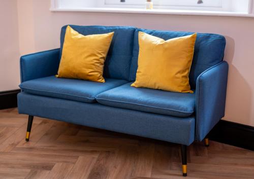 a blue couch with two yellow pillows on it at Oasis studio in the Heart of the City in Brighton & Hove