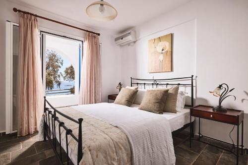 a bedroom with a large bed and a window at Tramontana Suites in Áyios Stéfanos