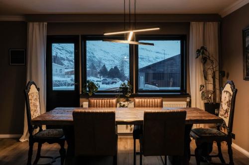 a dining room table with chairs and a large window at Botnahlid Villa in Seyðisfjörður