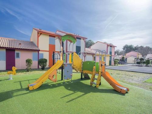 a playground with a slide in a yard with houses at Villa ROMA in Soustons