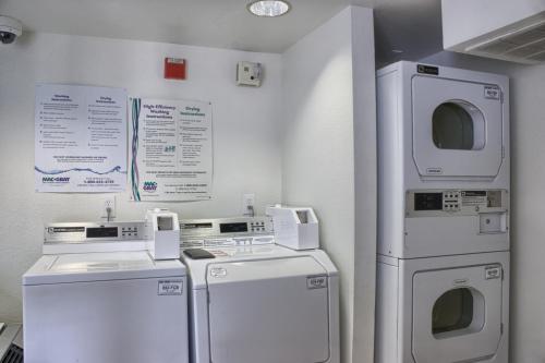 a laundry room with white appliances and signs on the wall at Motel 6-Seattle, WA - South in SeaTac