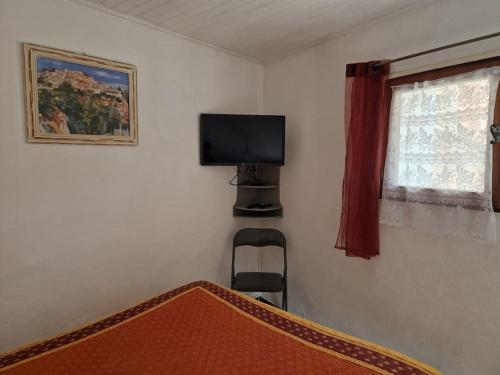 Schlafzimmer mit einem Bett, einem TV und einem Fenster in der Unterkunft Gîte Le Val des Fées classés deux étoiles in Roussillon
